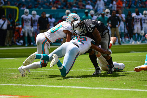 Miami Dolphins defensive back T.J. McDonald (22) and Miami Dolphins defensive back Minkah Fitzpatrick (29) try to tackle Oakland Raiders running back Marshawn Lynch (24)